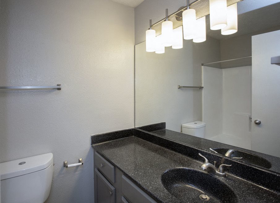A bathroom with a toilet, sink, and mirror.